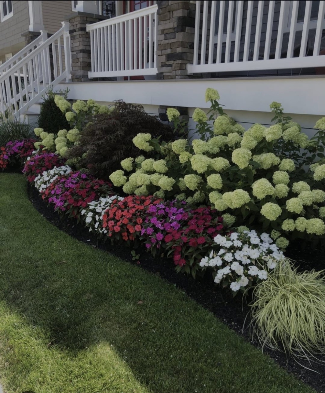 Hydrangea and impatiens border beside a porch